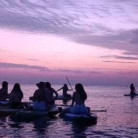 Paddleboarden bij zonsondergang langs de kust van Barcelona